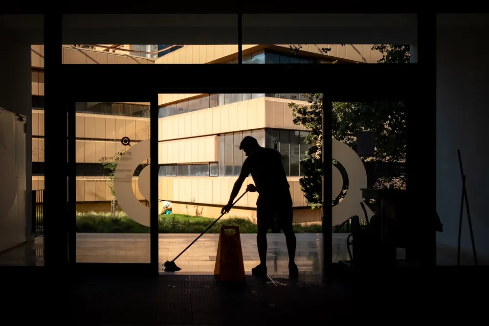 Worker sweeping an external entryway at dusk